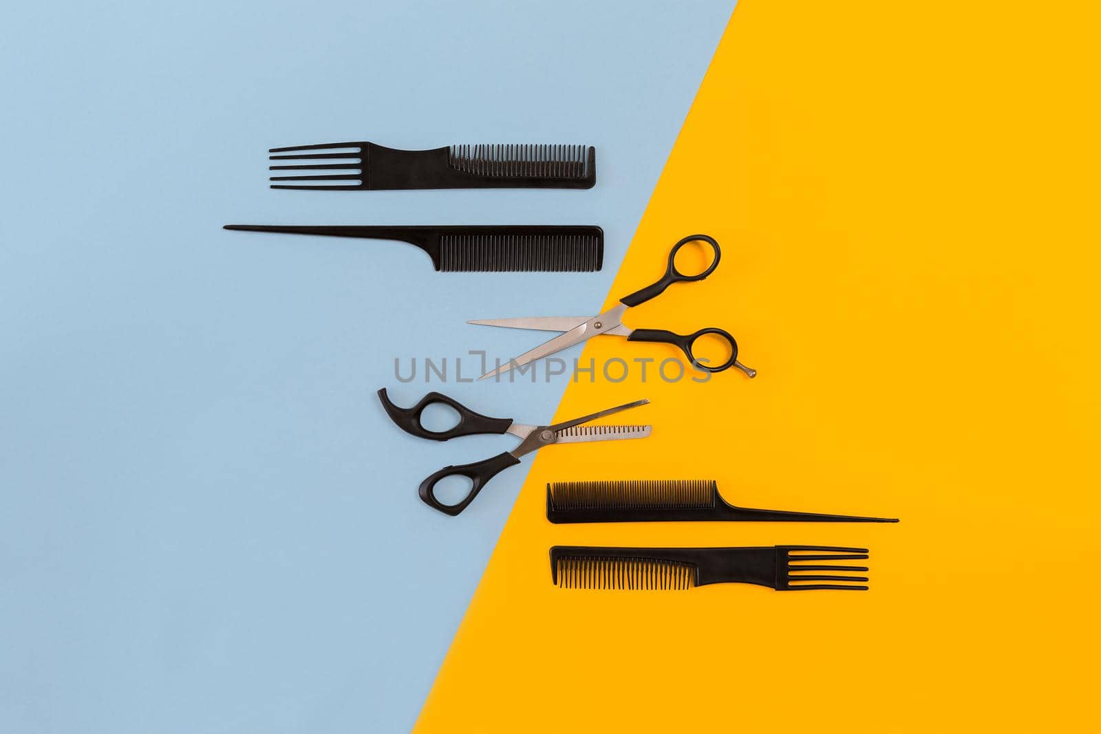 Hairdresser tools on blue and yellow background with copy space, top view, flat lay. Comb, scissors. Still life.