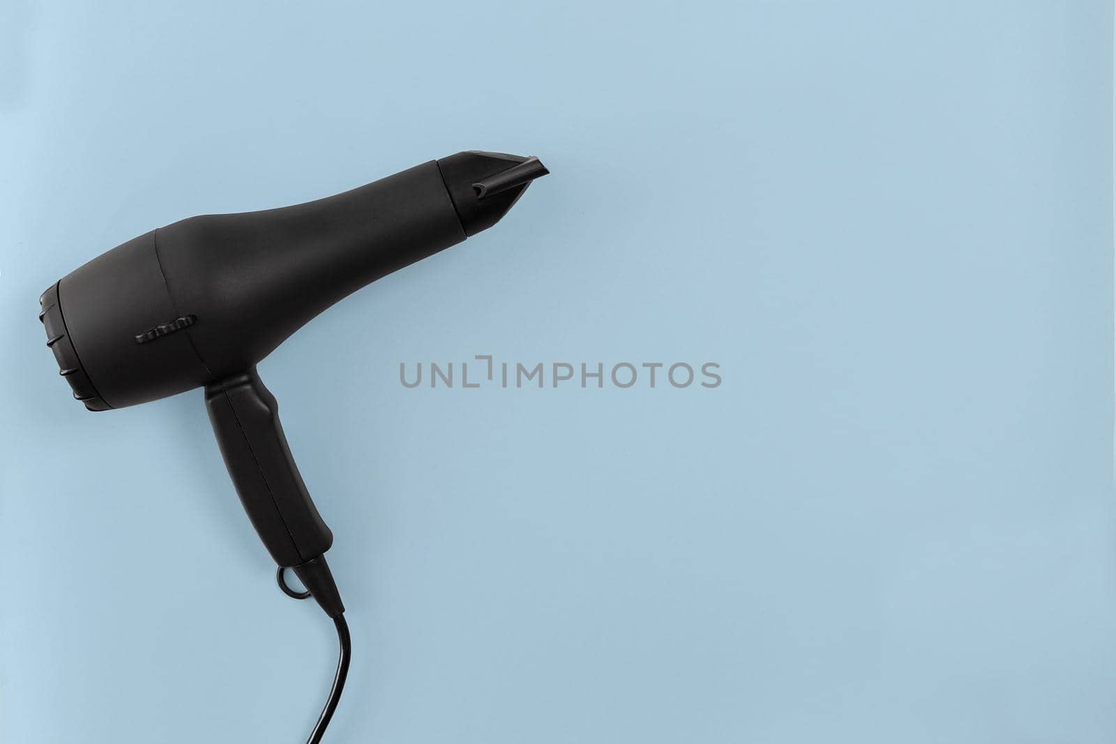 Black hair dryer on blue paper background by nazarovsergey