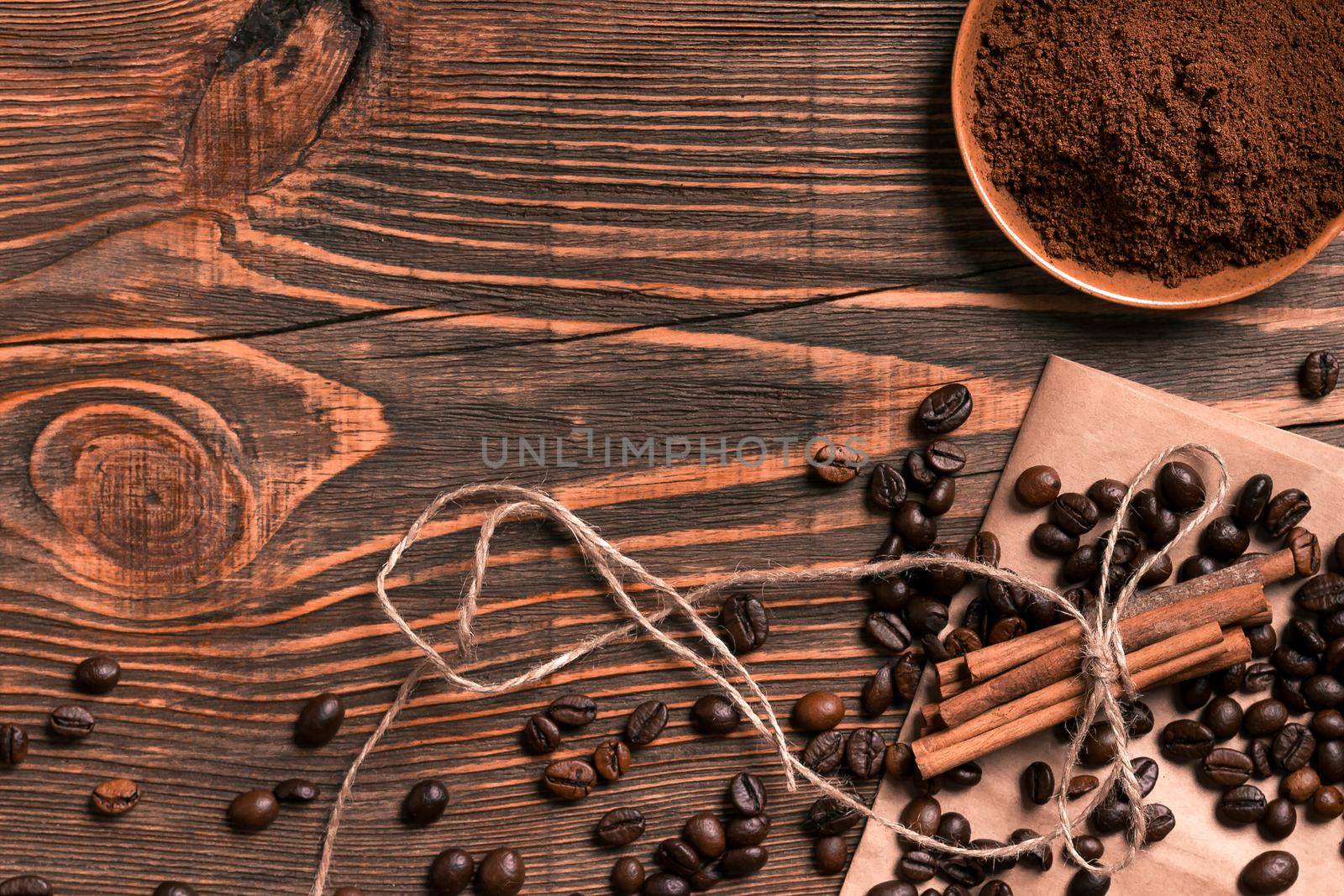 Coffee beans, cinnamon sticks and ground coffee on rustic wooden table, view from above with space for text. Still life. Mock-up. Flat lay