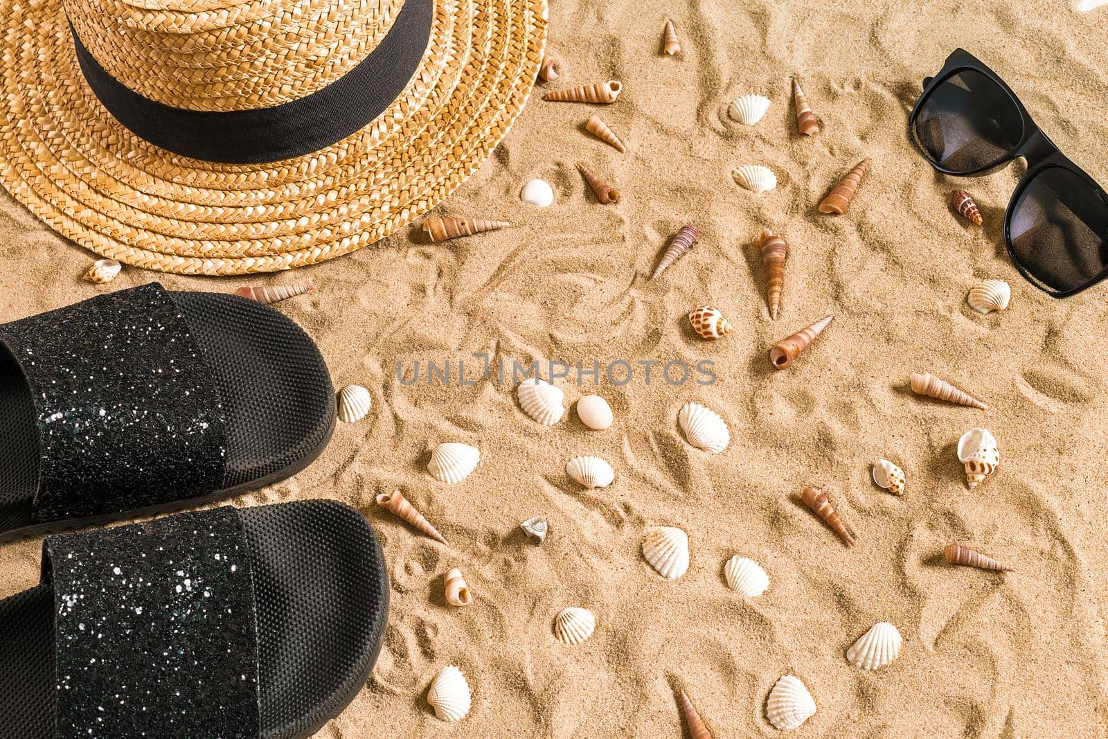 Summer beachwear, flip flops, hat, sunglasses and seashells on sand beach. by nazarovsergey