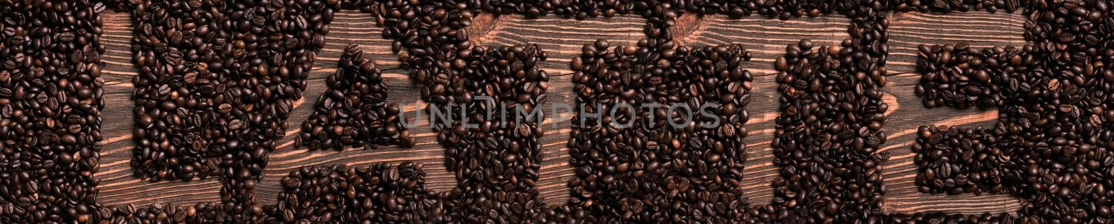 Latte word written with wooden letters on coffee beans heap. Top view