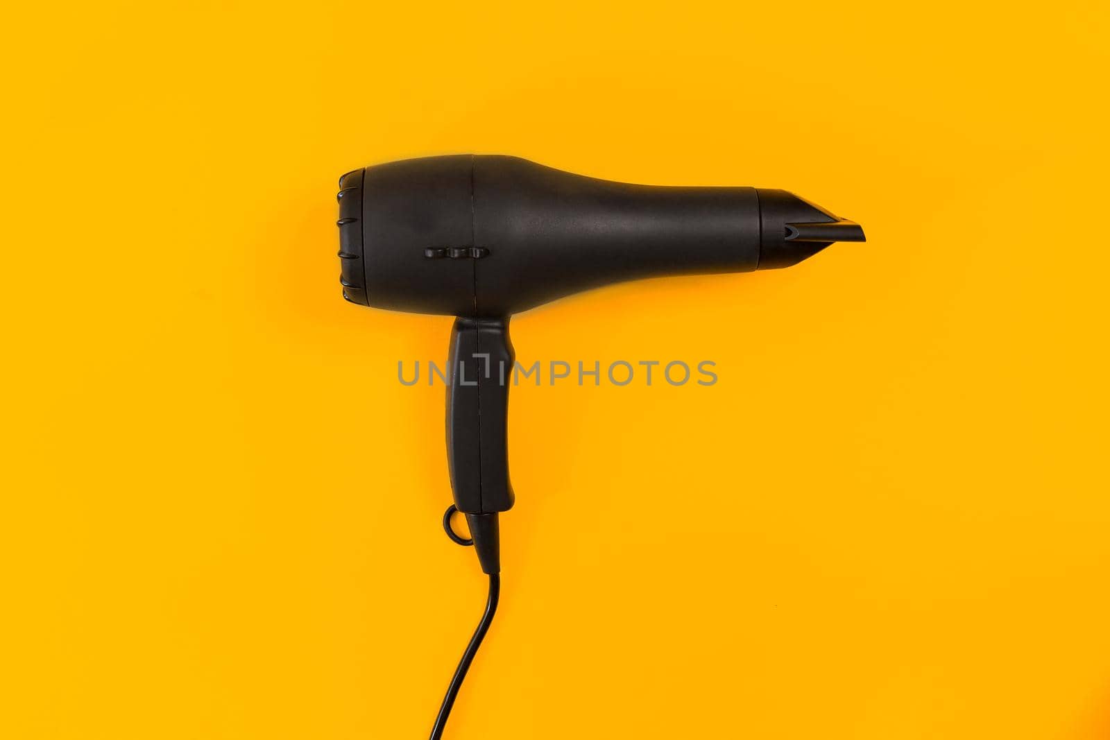 Black Hair dryer on orange background. Top view. Still life. Flat lay. Copy space