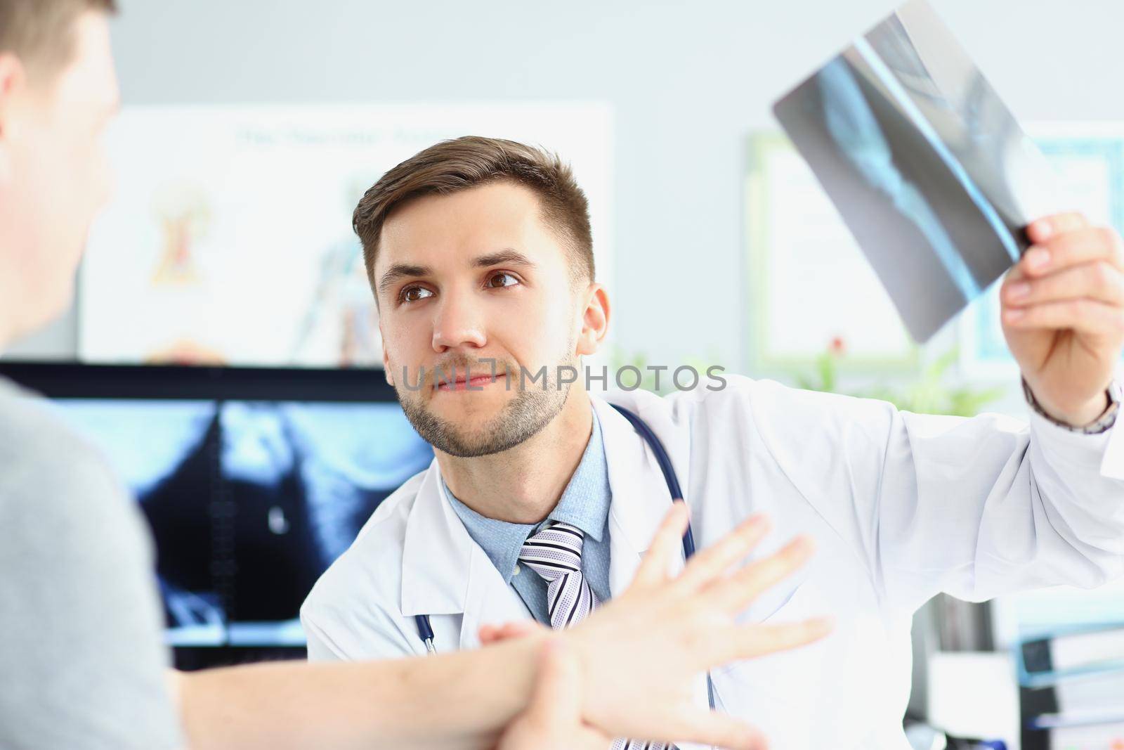 Portrait of smiling doctor talking with patient about good x ray results. Doc looking at visitor with happiness. Recovery, medical and healthcare concept