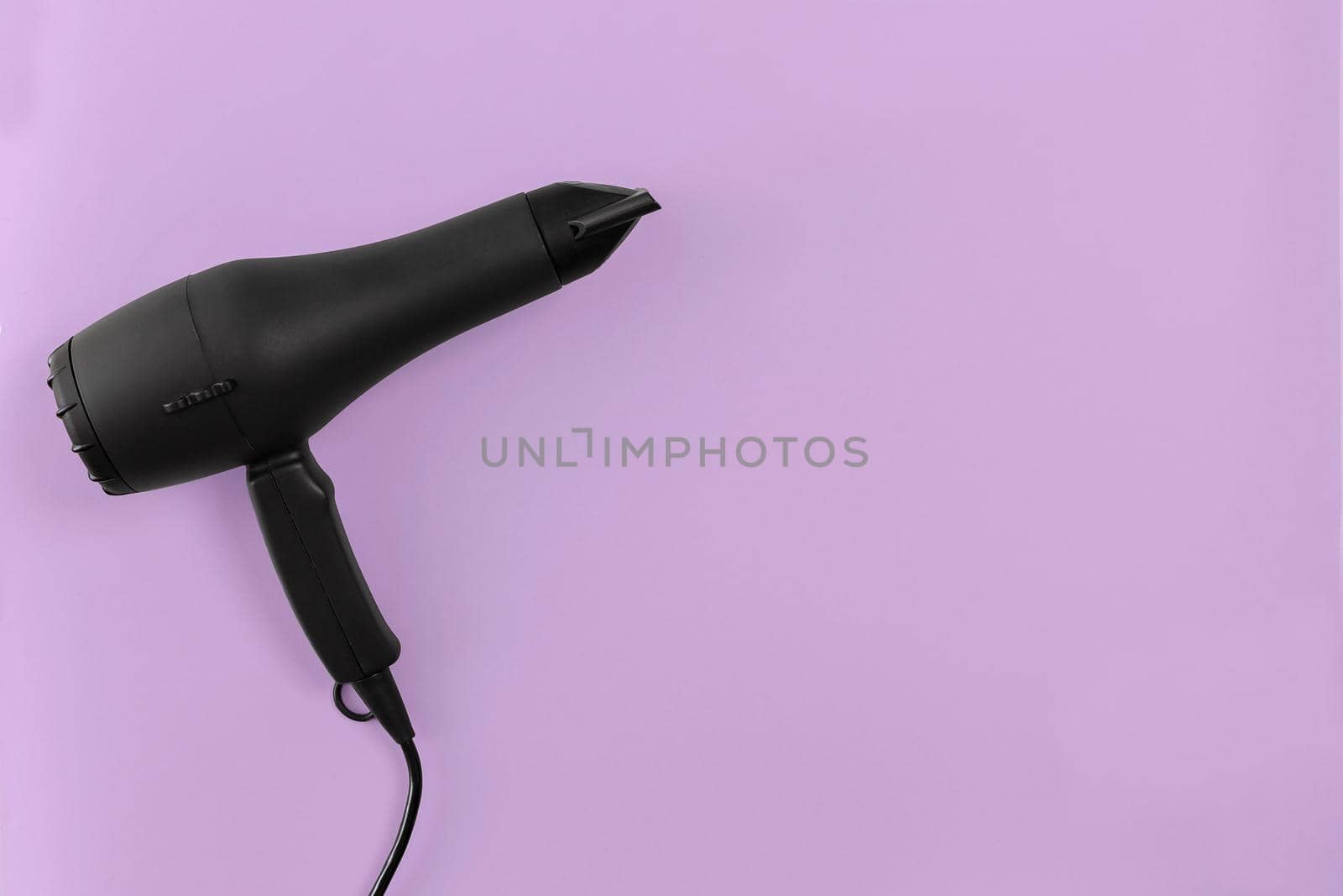 Black hair dryer on lilac paper background by nazarovsergey