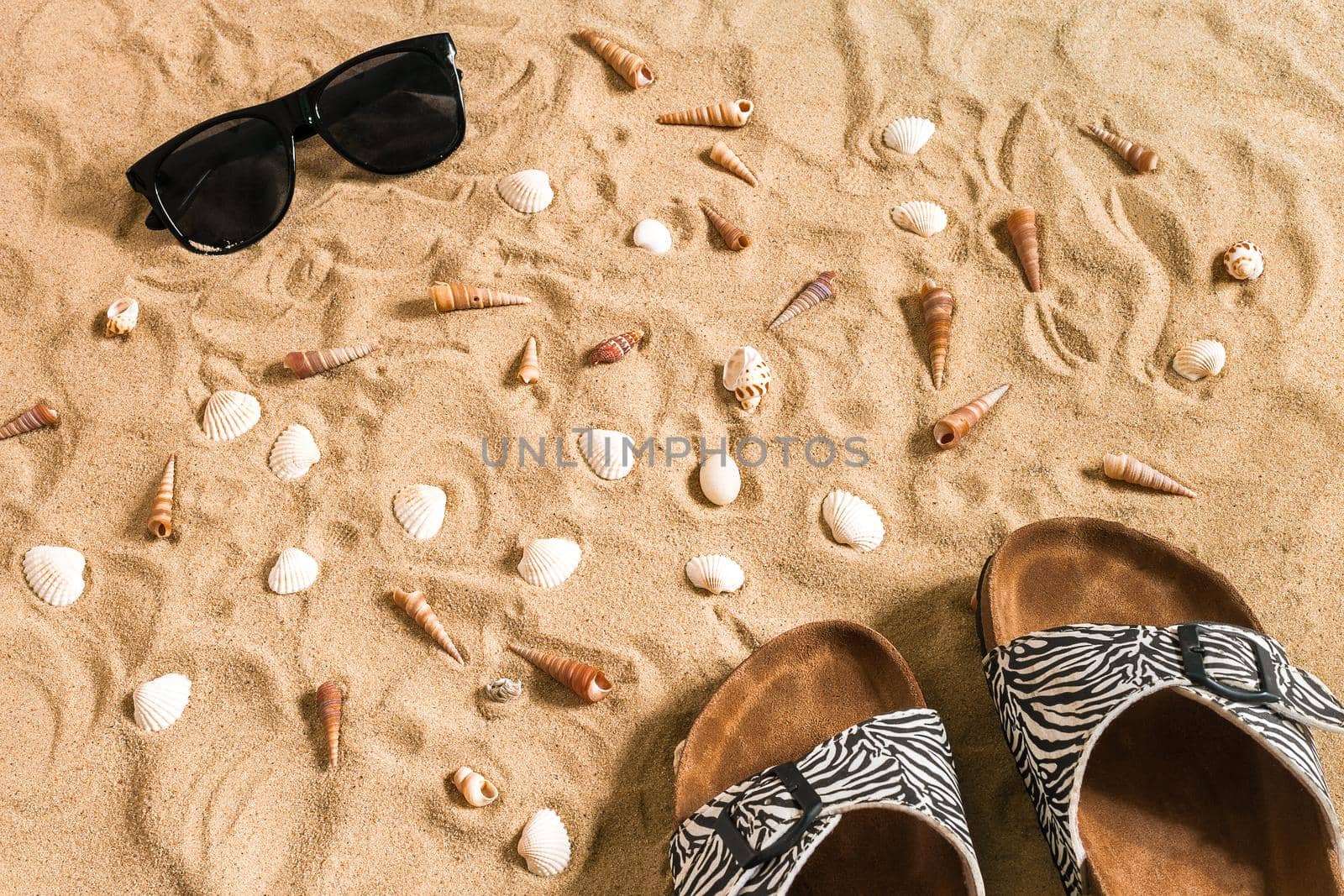 Black flip-flops and sunglass, seashell on sand. With place for your text. Top view. Copy space. Still life mockup flat lay