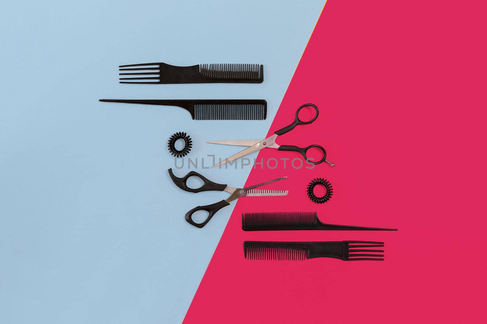 Hairdresser tools on blue and pink background with copy space, top view, flat lay. Comb, scissors. Still life.