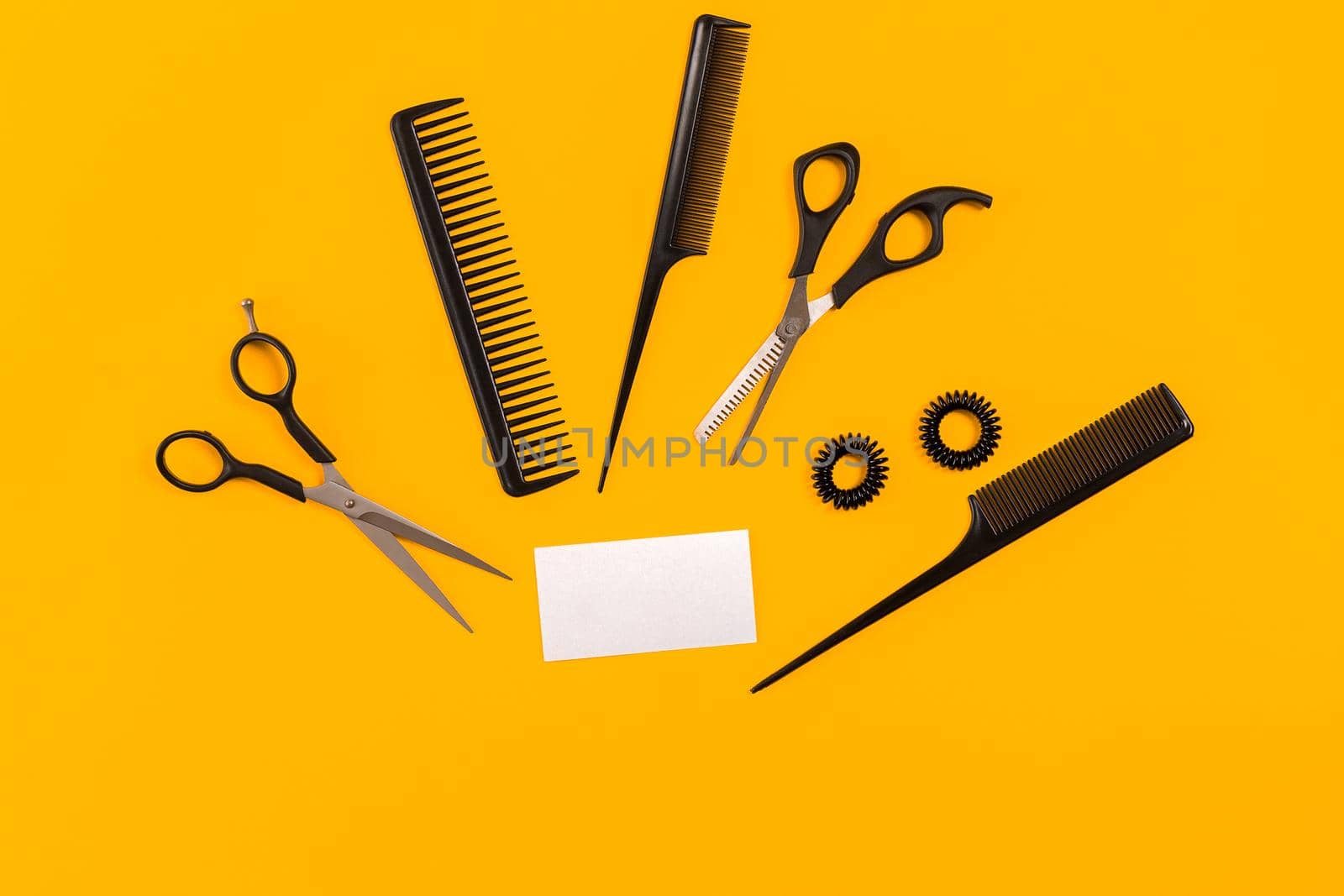 Hairdresser tools on yellow background with copy space, top view, flat lay. Comb, scissors, thinning scissors, hair clip. Still life.