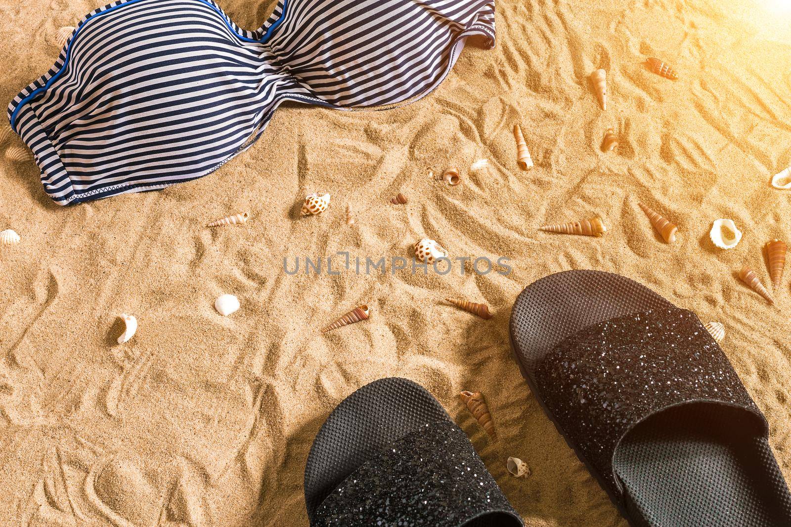 Summer bikini and accessories stylish beach set, Beach bikini summer outfit and sea sand as background, Top View, Concept by nazarovsergey