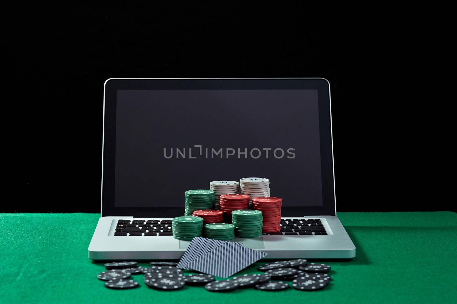 Casino chips and cards on keyboard notebook at green table. by nazarovsergey