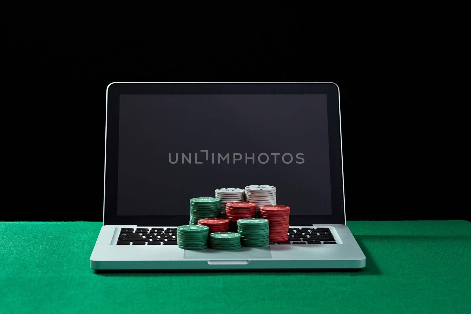 Image of casino chips on a keyboard notebook at green table. Concept for online gambling, poker, virtual casino.