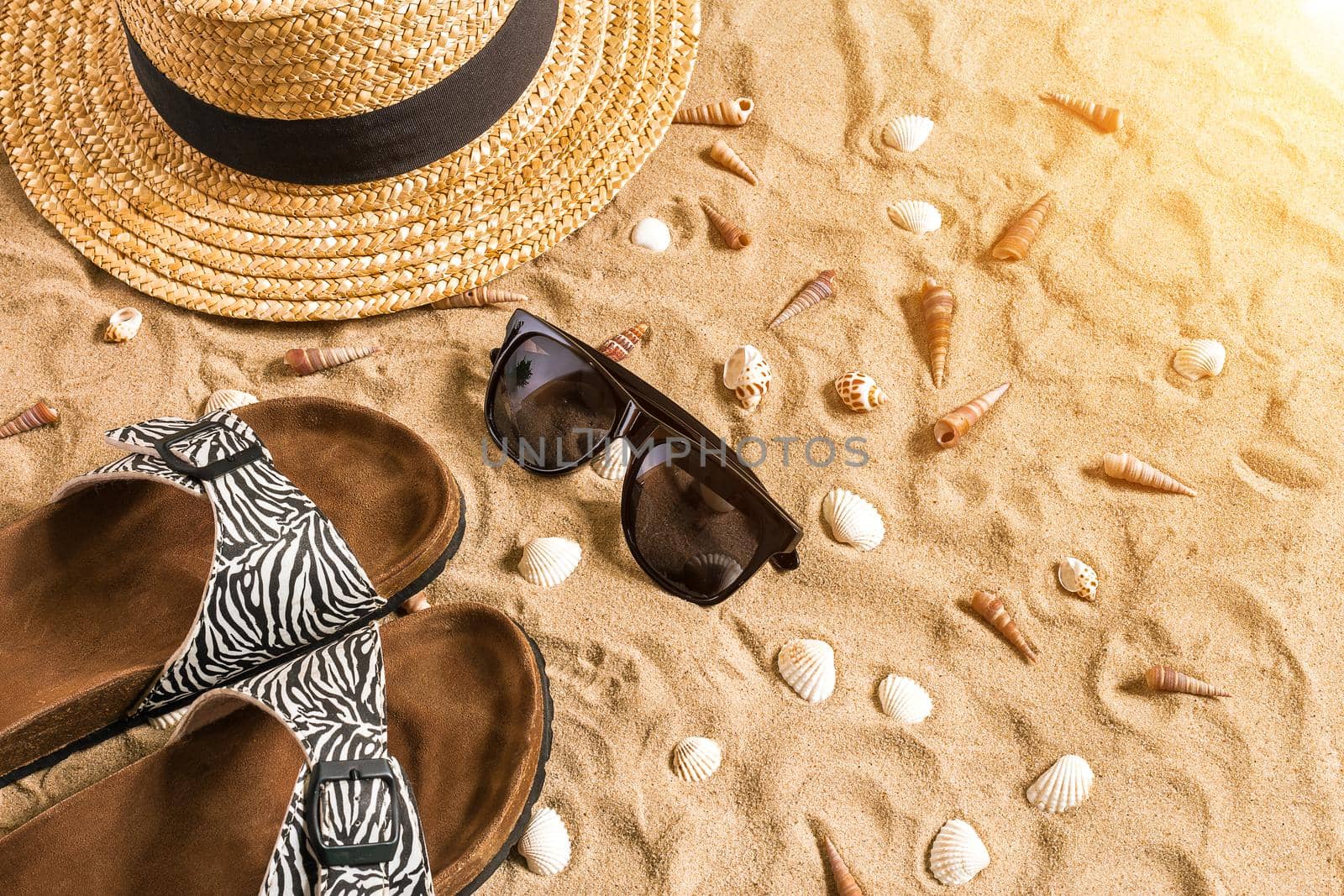 Summer beachwear, flip flops, hat, sunglasses and seashells on sand beach. by nazarovsergey