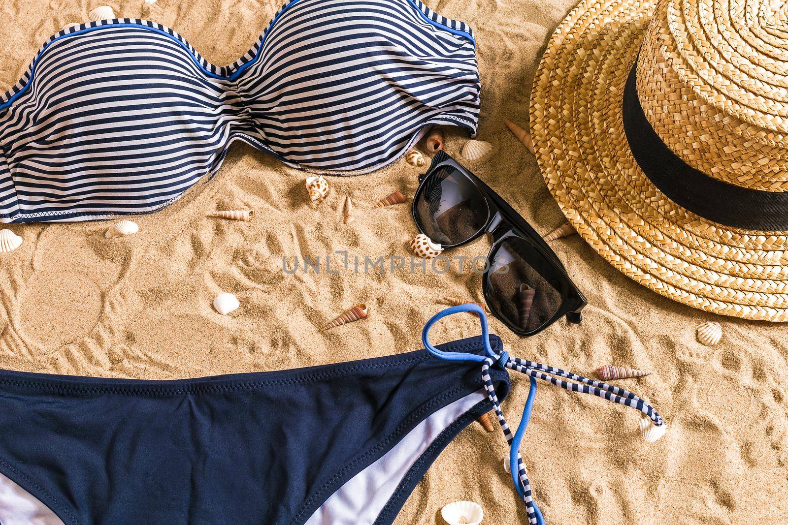 Summer bikini and accessories stylish beach set, Beach bikini summer outfit and sea sand as background, Top View, Concept. Copy space