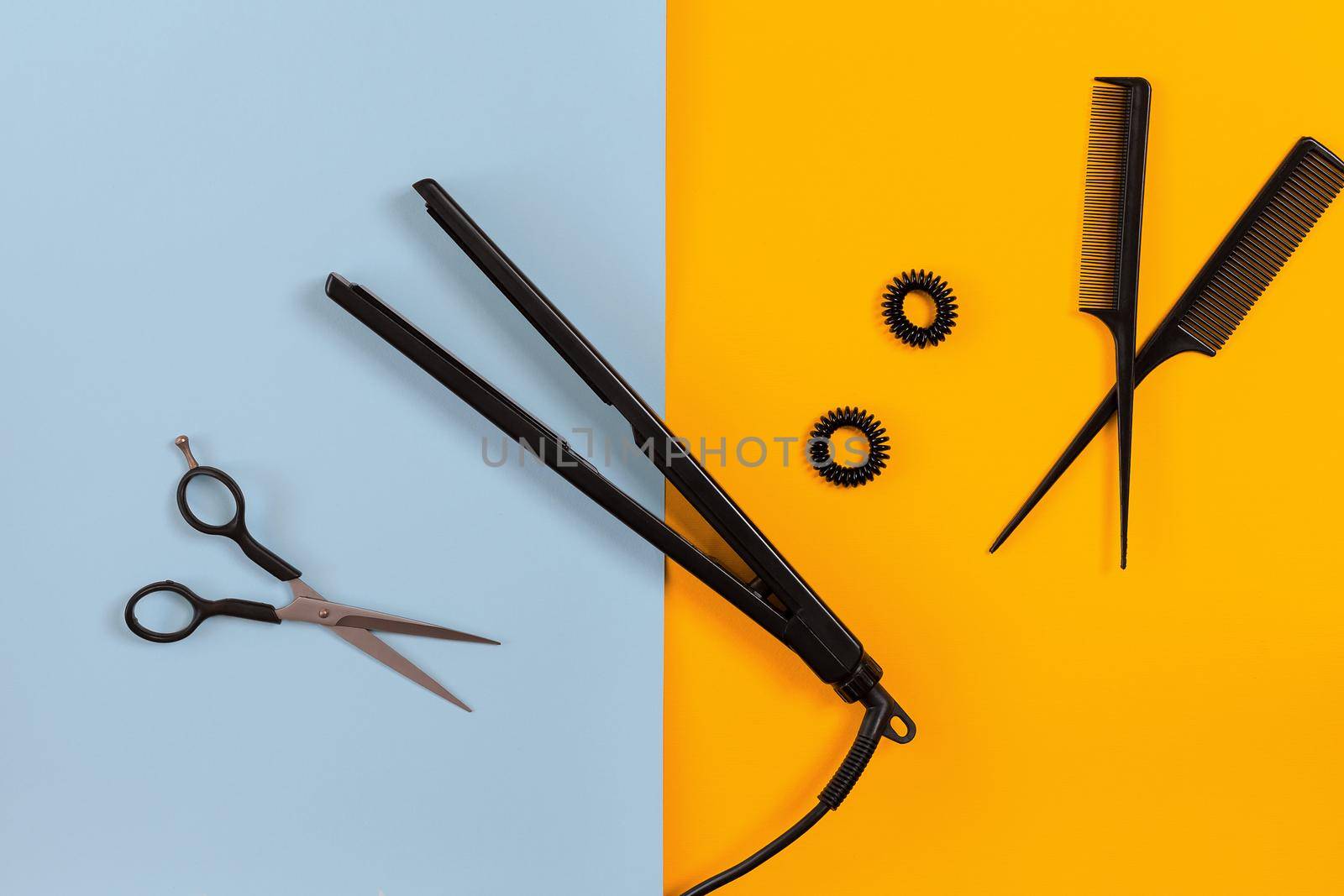 Hairdresser set with various accessories on orange and blue background. Top view. Copy space. Still life. Mock-up. Flat lay