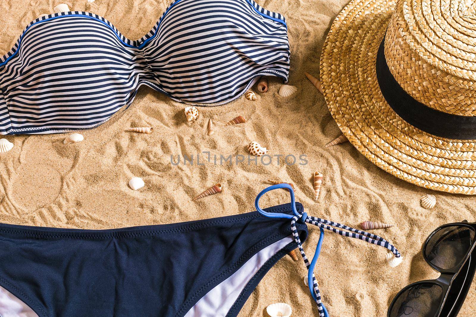 Summer bikini and accessories stylish beach set, Beach bikini summer outfit and sea sand as background, Top View, Concept by nazarovsergey