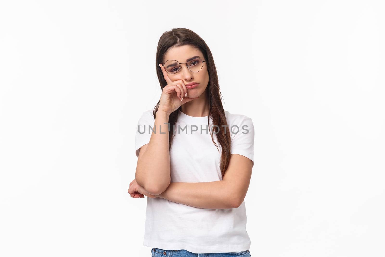 Waist-up portrait of bored, uninterested young brunette female in glasses, feel tired or sleepy, listening to boring conversation, lean on hand look reluctant with lack of interest, white background.