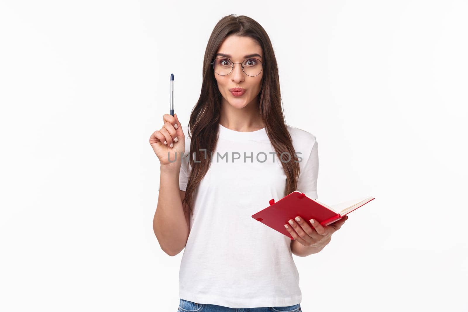 Creative enthusiastic young woman have great idea, writing it down in her notebook not to forget, raising pen in eureka sign, smiling excited, prepare plan or daily schedule, white background.
