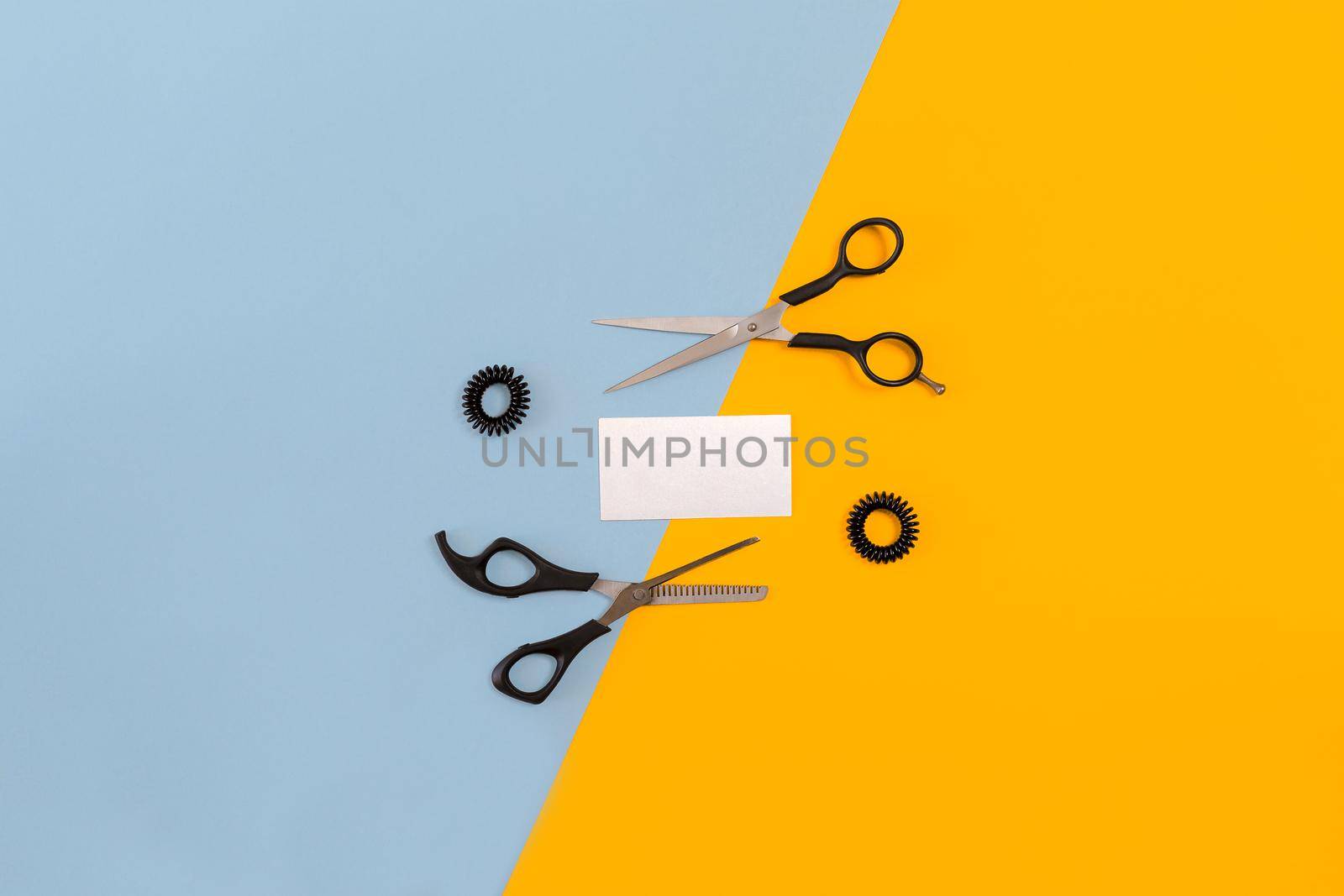 Hairdresser set with various accessories on orange and blue background. Top view. Copy space. Still life. Mock-up. Flat lay