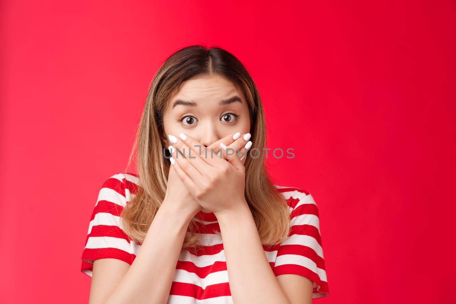 Close-up shocked asian woman gasping speechless press hands lips raise eyebrows impressed stunned, stare camera hear unbelievable shook news stand red background astonished. Copy space