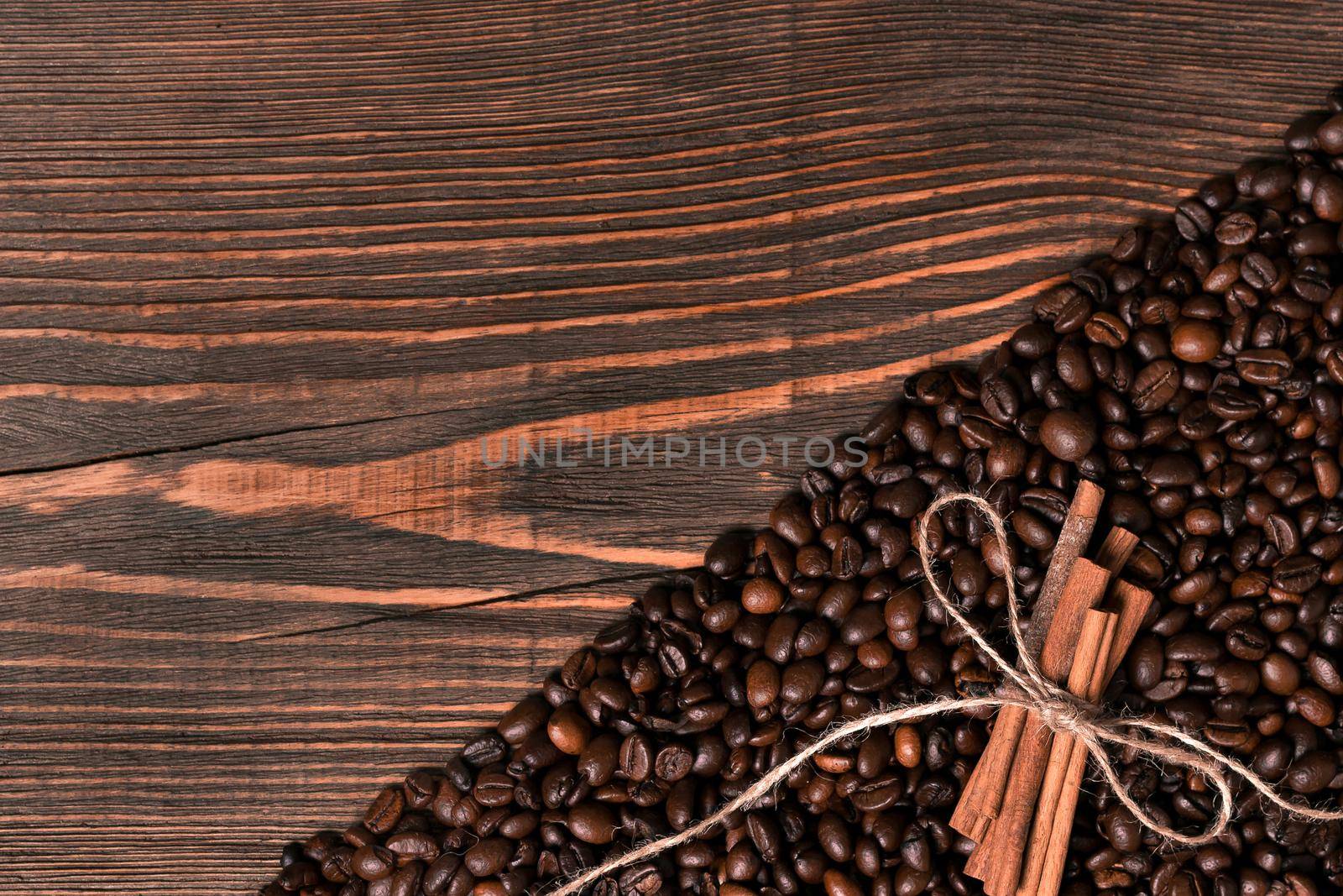 Coffee beans on wooden table background with cinnamon. Top view. Still life. Copy space. Flat lay.