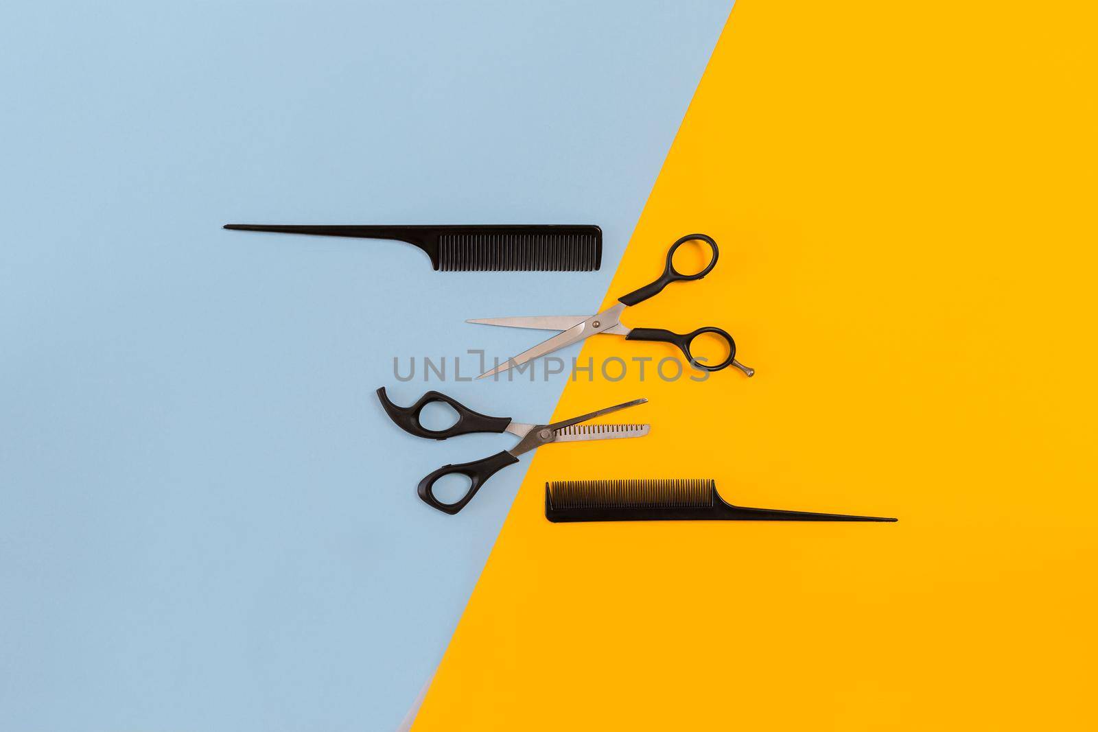 Hairdresser set with various accessories on orange and blue background. Top view. Copy space. Still life. Mock-up. Flat lay