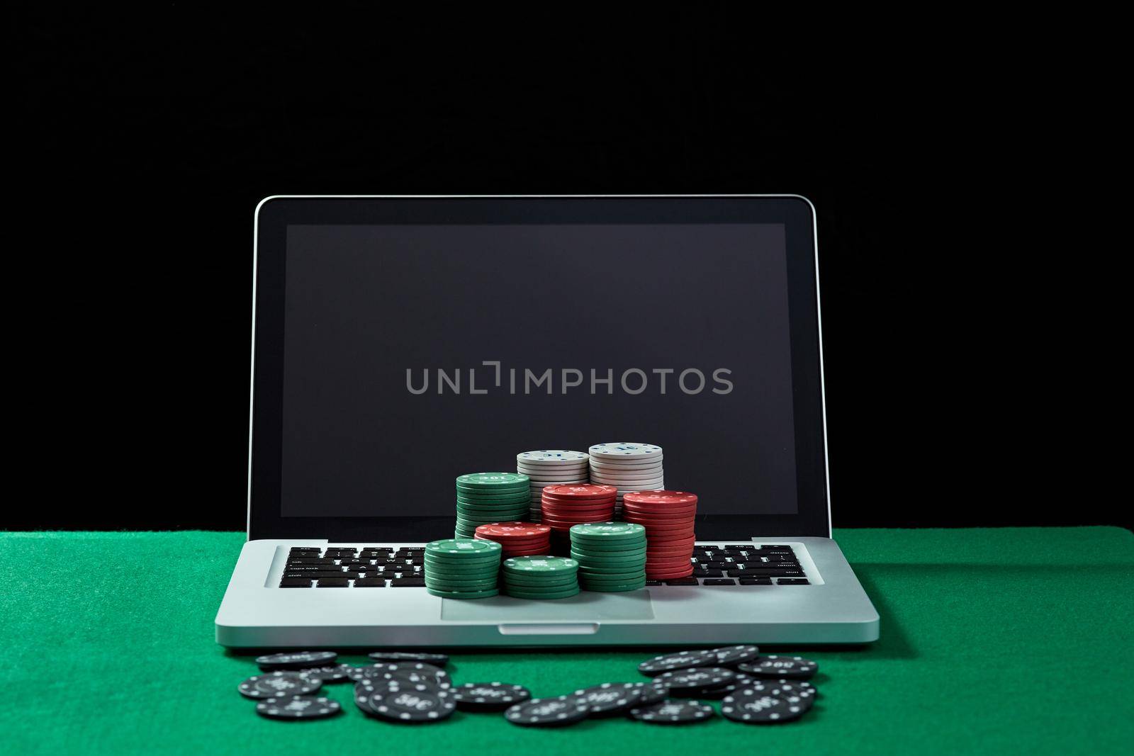 Image of casino chips on a keyboard notebook at green table. Concept for online gambling, poker, virtual casino.