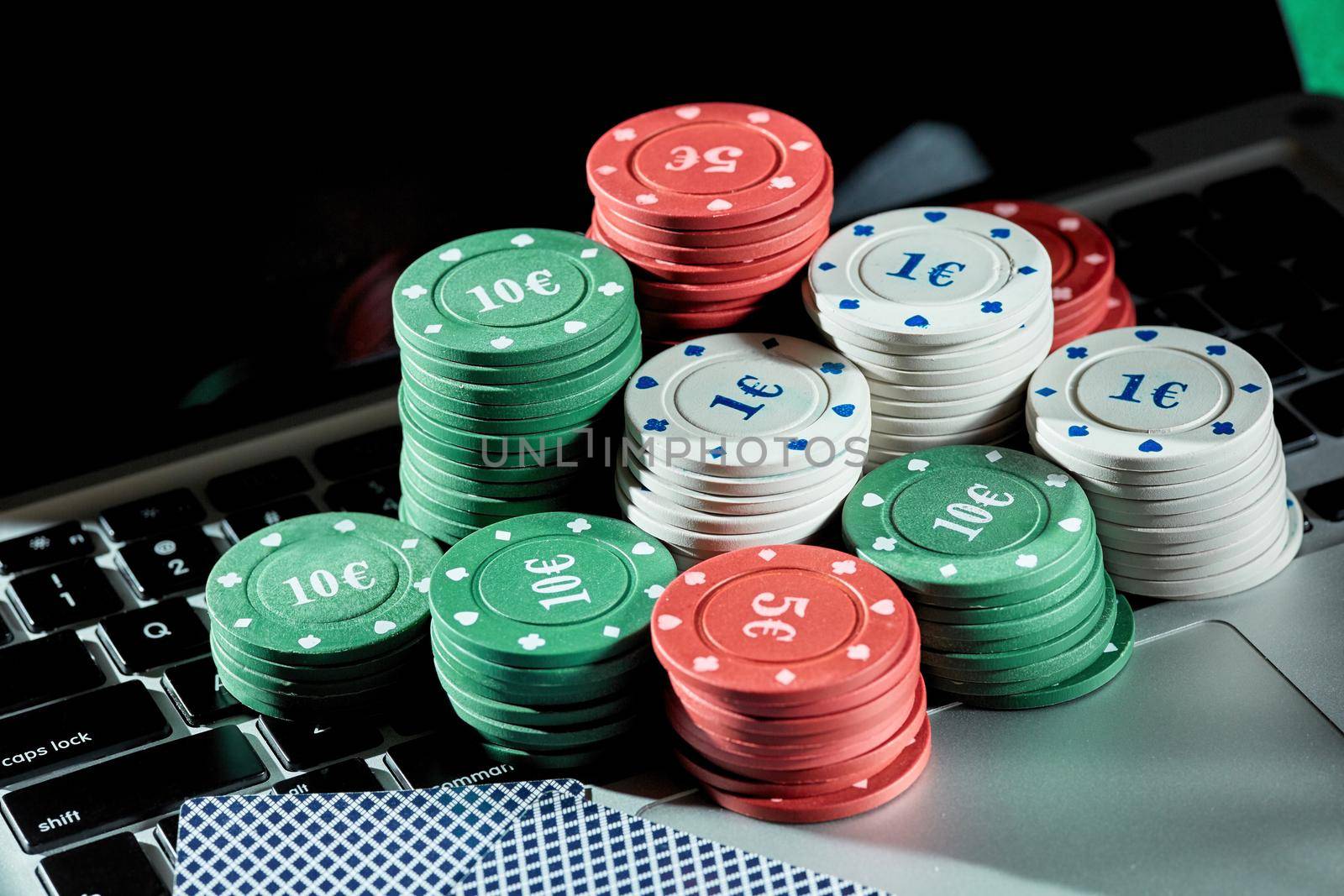 Casino chips and cards on laptop to play gambling online. by nazarovsergey