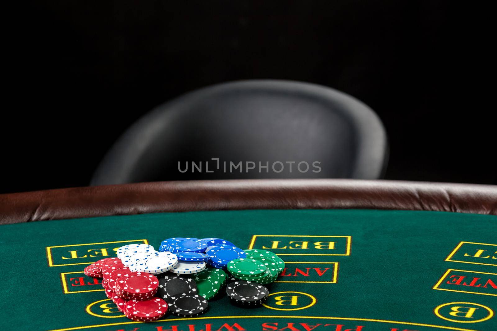 Poker play. Chips on the green table and empty chair