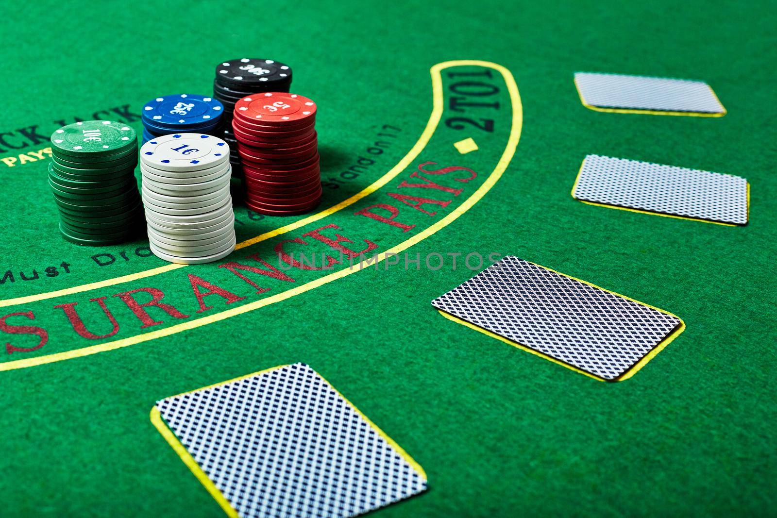 Casino chips and deck of cards lying on green casino table, poker game concept.