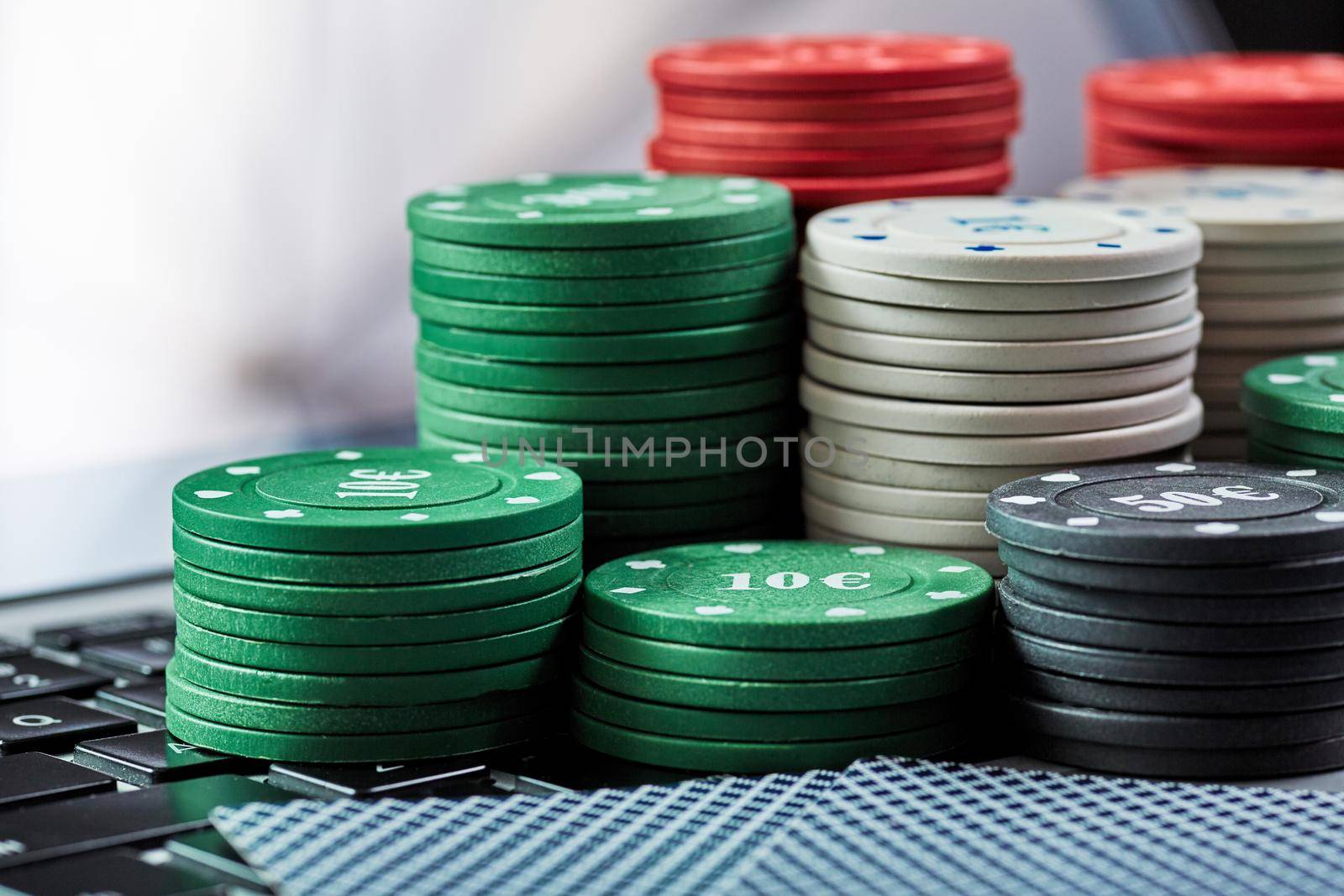 View of casino chips, cards on laptop to play online. by nazarovsergey