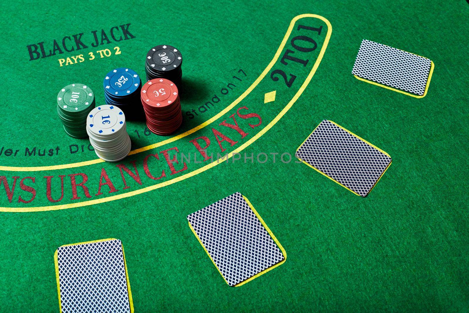 Casino chips and deck of cards lying on green casino table, poker game concept, top view.