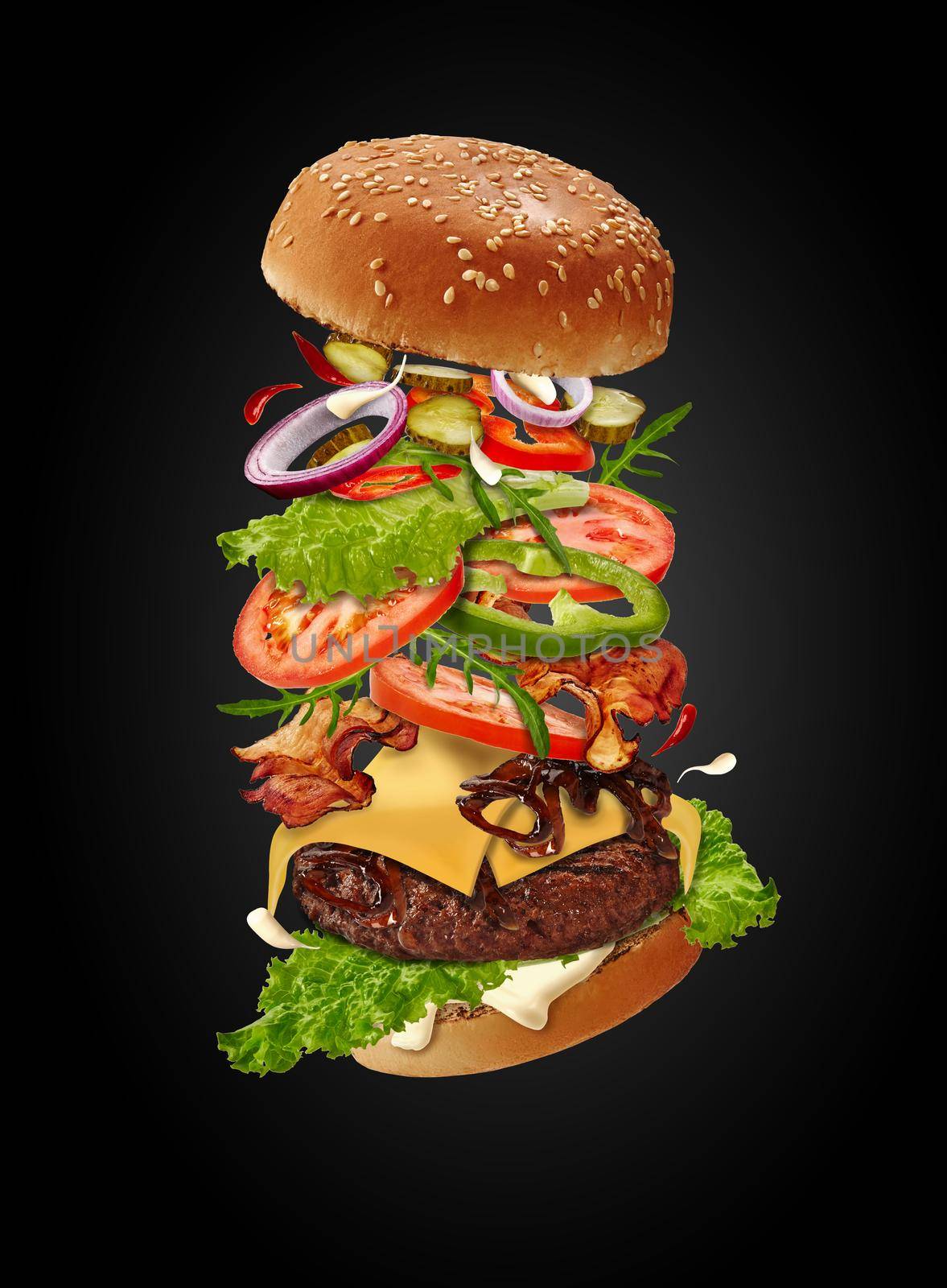 Maxi burger with flying ingredients against black background. Ham, beef cutlet, cheese, mayonnaise, vegetables and greens. Close up, copy space by nazarovsergey