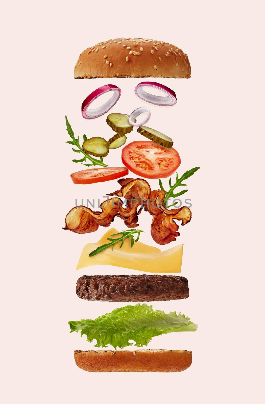 Palatable big burger with flying ingredients against light pink background. Ham, beef cutlet, cheese, vegetables and greens. Close up, copy space by nazarovsergey