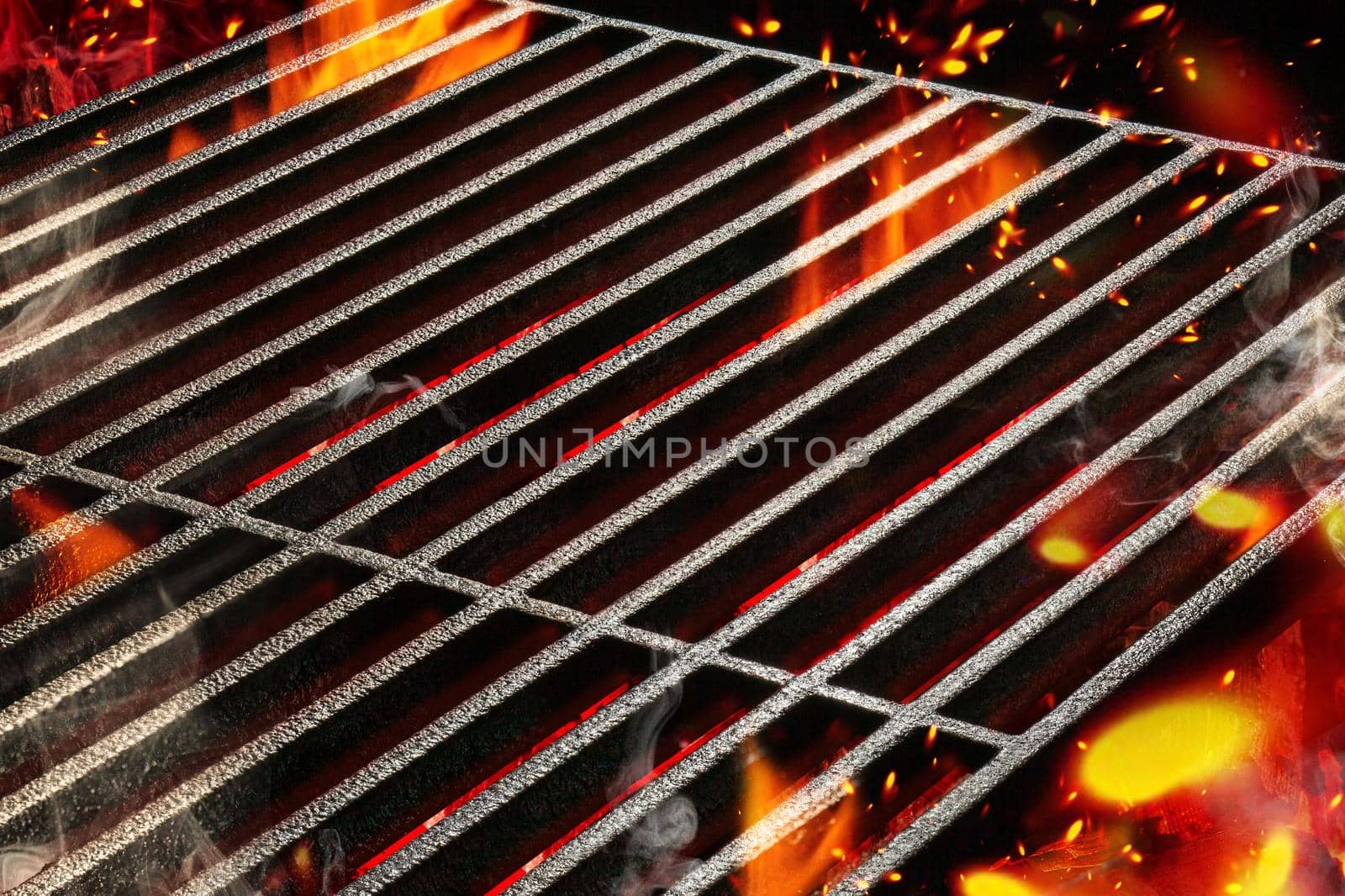Hot empty portable summer barbecue BBQ grill with bright flaming fire and ember charcoal. Waiting for the placement of your food. Cookout concept. Close up