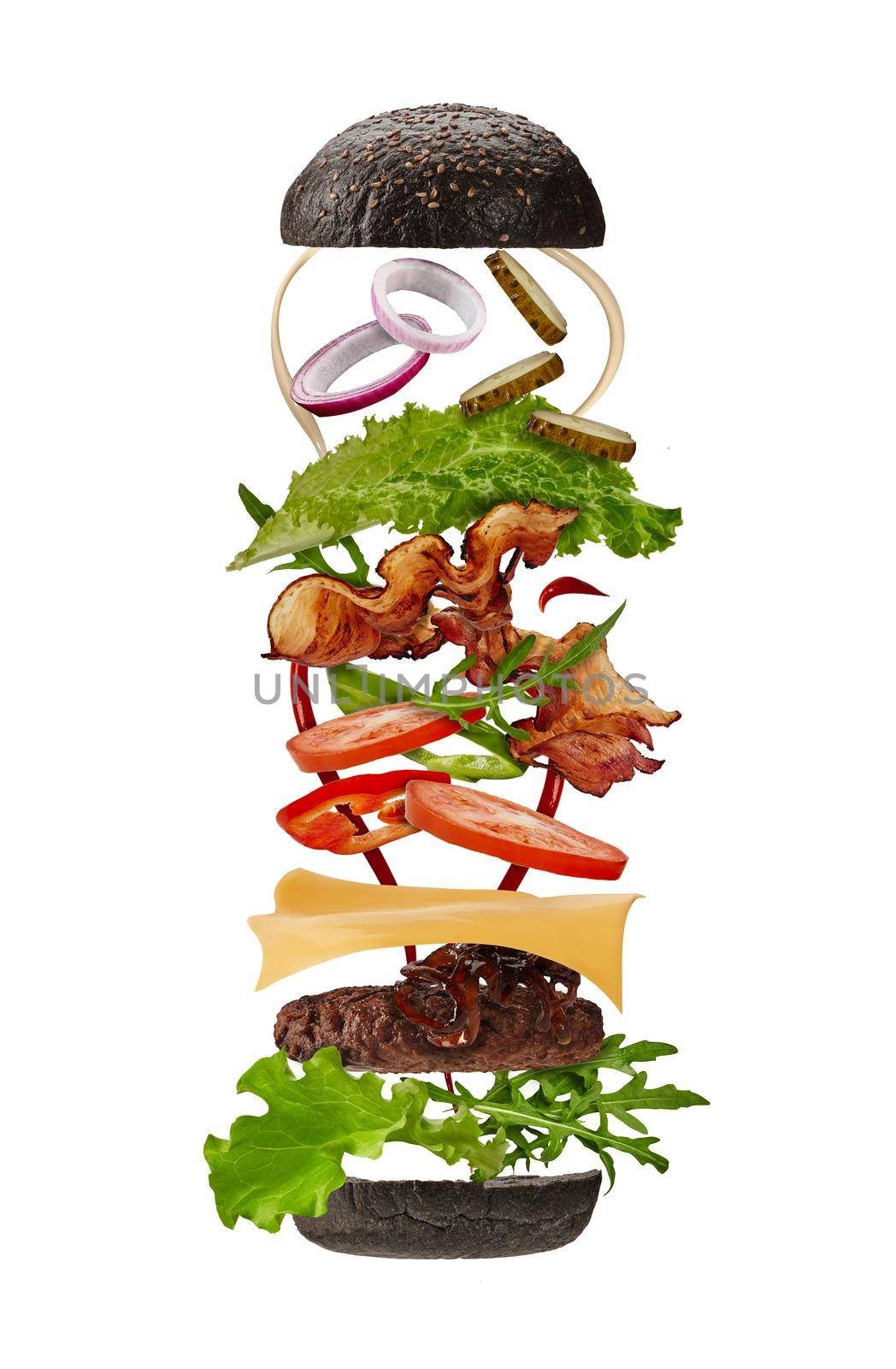 Big black burger with flying ingredients isolated on white background. Ham, beef cutlet, cheese, mayonnaise, ketchup, vegetables and greens. Concept of cooking and fast food. Close up, copy space