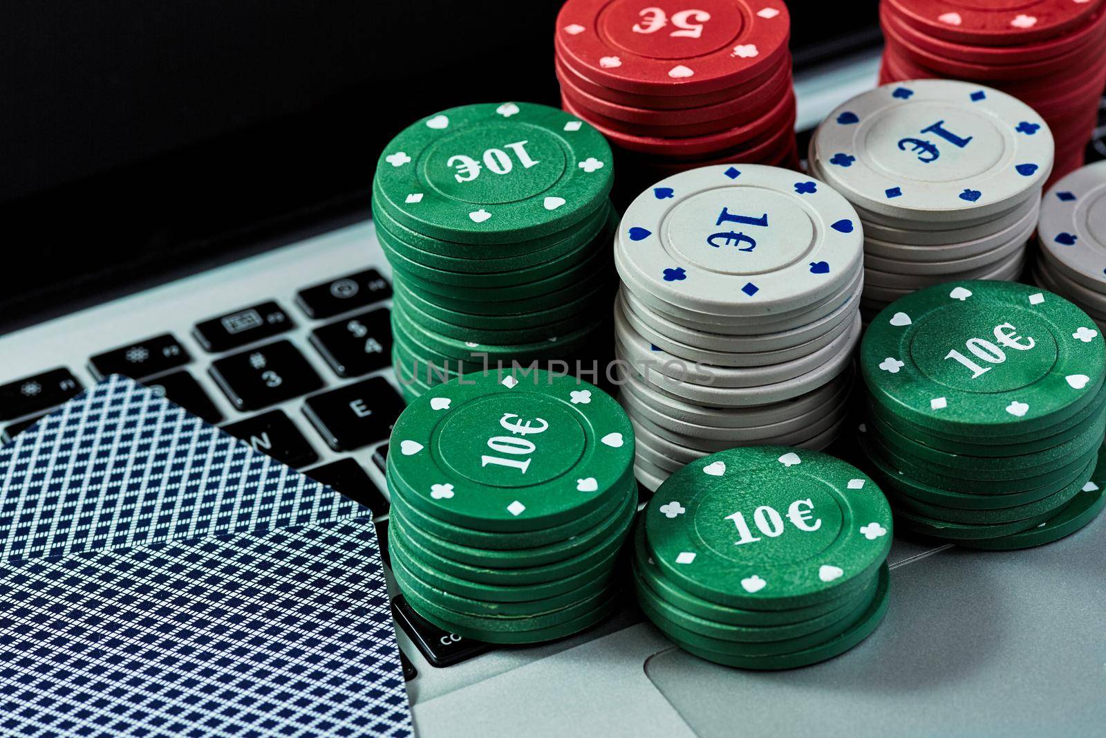 View of casino chips and cards on a laptop to play online. Concept for online gambling, poker, virtual casino.