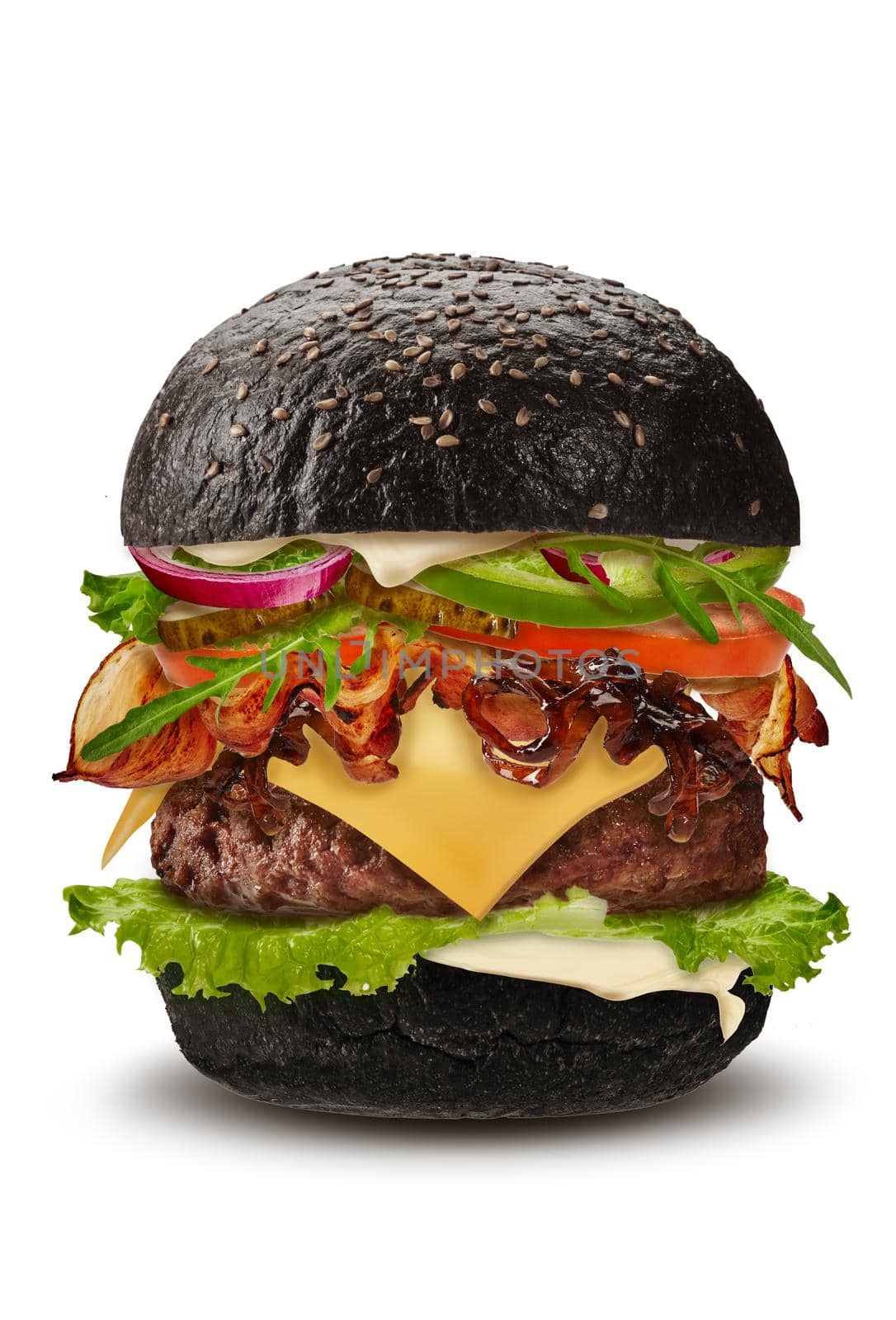 Big black burger isolated on white background. Ham, beef cutlet, cheese, mayonnaise, vegetables and greens. Cooking, fast food. Unhealthy nutrition. Close up, copy space