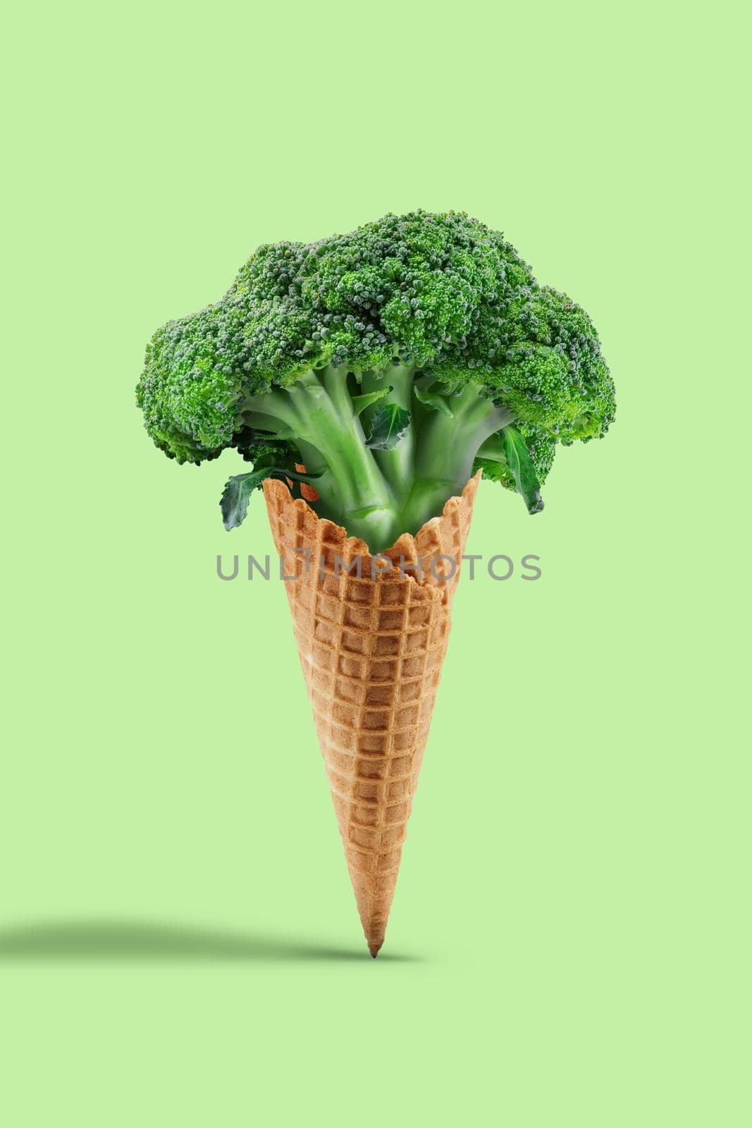 Raw broccoli in a wafer cone against light green background. Concept of healthy nutrition, food and seasonal vegetables harvest. Close up, copy space