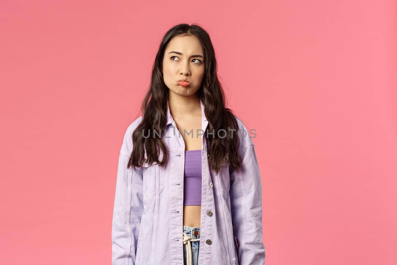 Waist-up portrait of upset gloomy stylish korean girl pouting and looking upper left corner with regret and envy, daydreaming about awesome party she missed, pink background by Benzoix