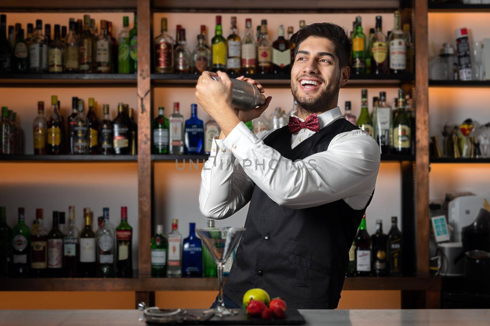 Bartender shaking cocktail shaker in cocktail bar by HERRAEZ