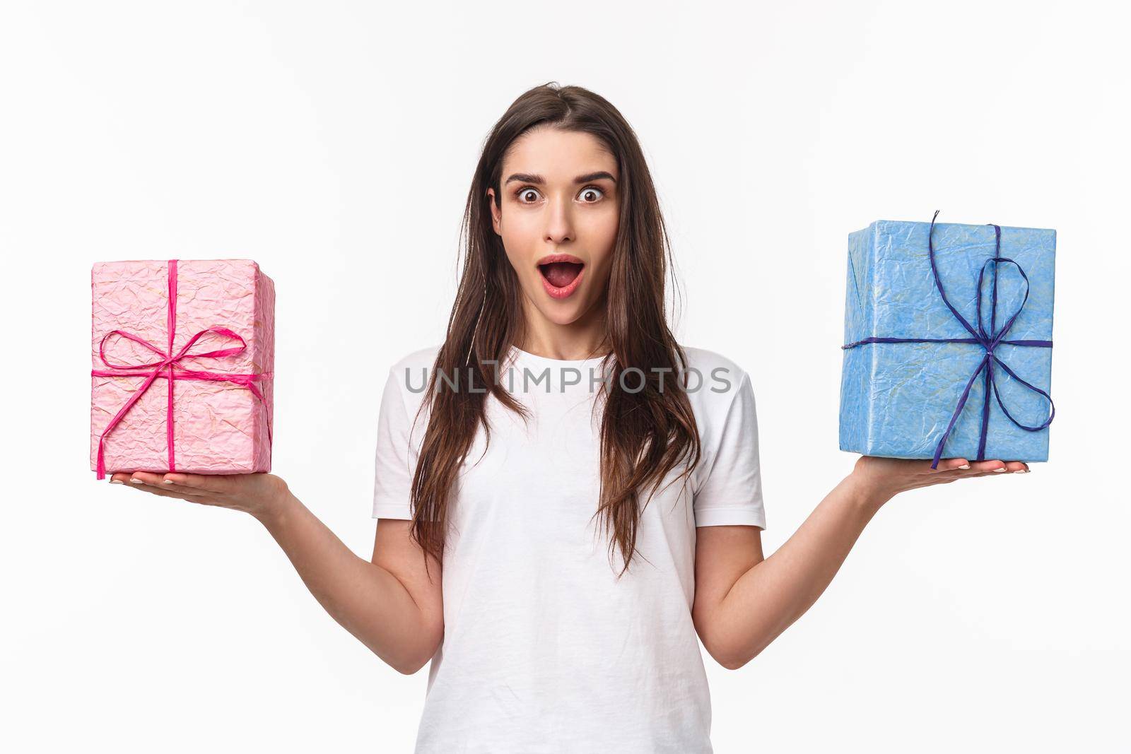 Celebration, holidays and presents concept. Portrait of surprised, excited beautiful young woman holding two box with gifts in both hands spread sideways, open mouth astonished, white background.