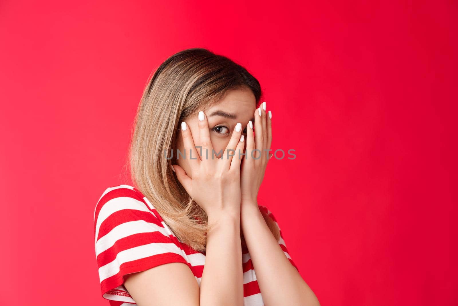 Not looking swear. Cute peeking young girl close eyes palms turn away stare one eye camera curiously, wanna see what happening, dying interest know what happening, stand red background by Benzoix