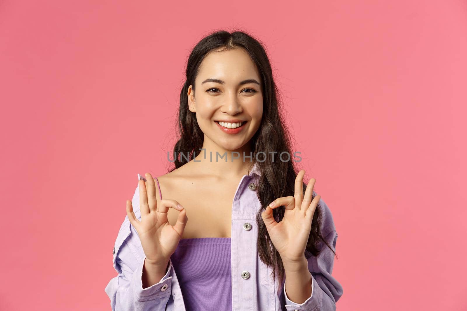 Close-up portrait of young relaxed pretty asian girl saying everything under control, no problem sign, show okay gesture and smiling as assuring all good, agree and approve excellent product by Benzoix