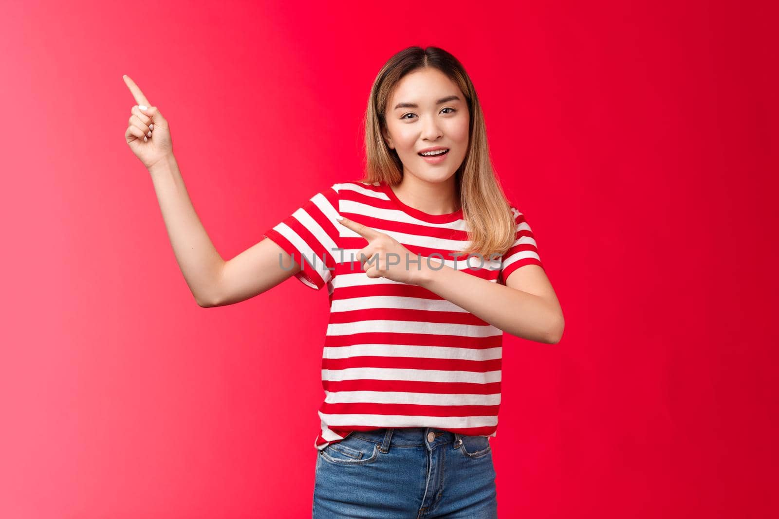 Enthusiastic friendly modern asian blond girl suggest perfect place hang promo pointing upper left corner smiling look camera assertive introduce project, recommend link, stand red background by Benzoix