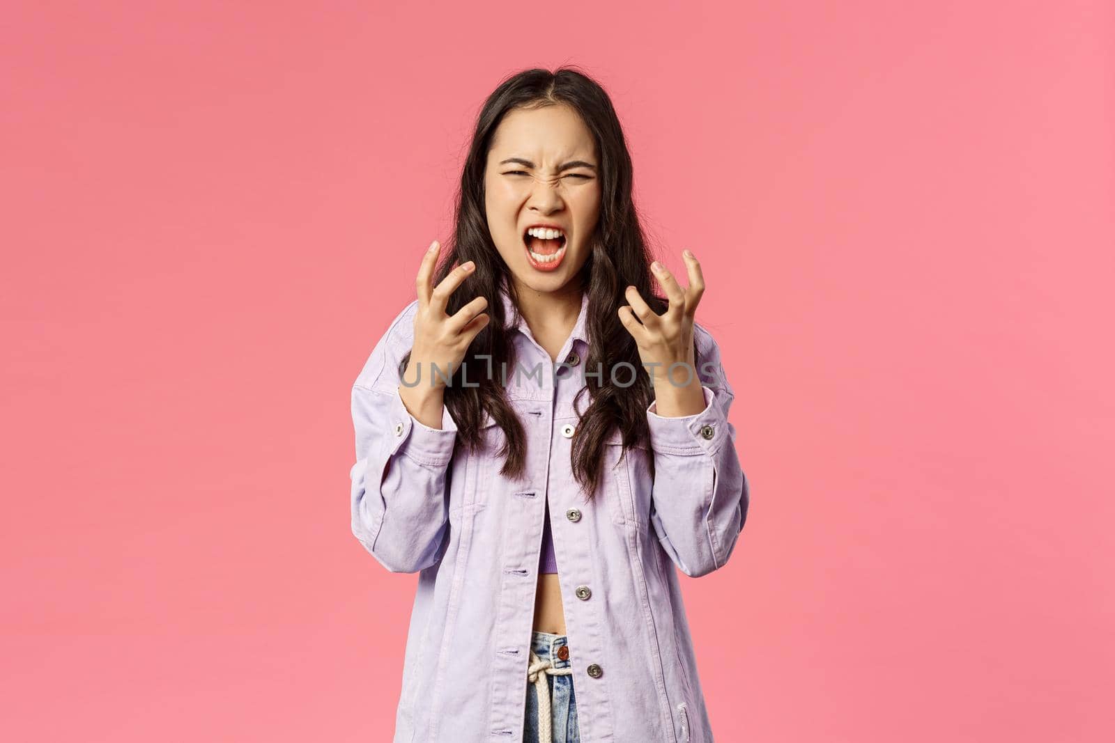 I hate all of you. Portrait of outraged, annoyed and angry young girl, teenage korean female screaming furious, grimacing and squeeze hands into fists from anger, losing temper, pink background.