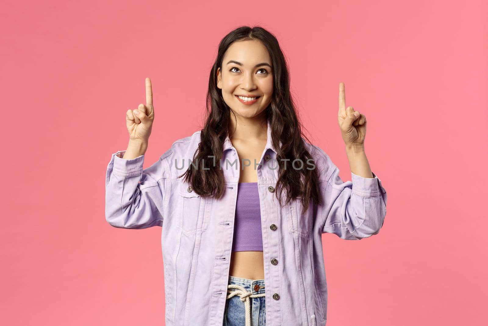Fashion, beauty and lifestyle concept. Portrait of young stylish woman in denim jacket, crop-top pointing fingers up, smiling and look amused, interested, found product, show promo by Benzoix