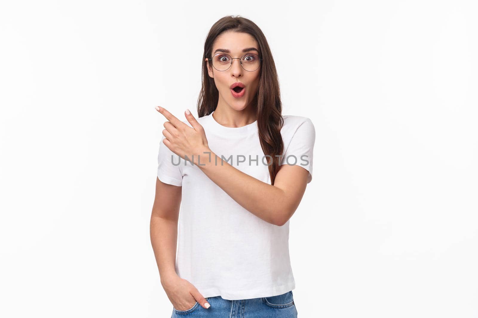 Portrait of impressed and enthusiastic, thrilled brunette female student talking about great opportunity travelling abroad, studying cool university program, pointing finger upper left corner by Benzoix