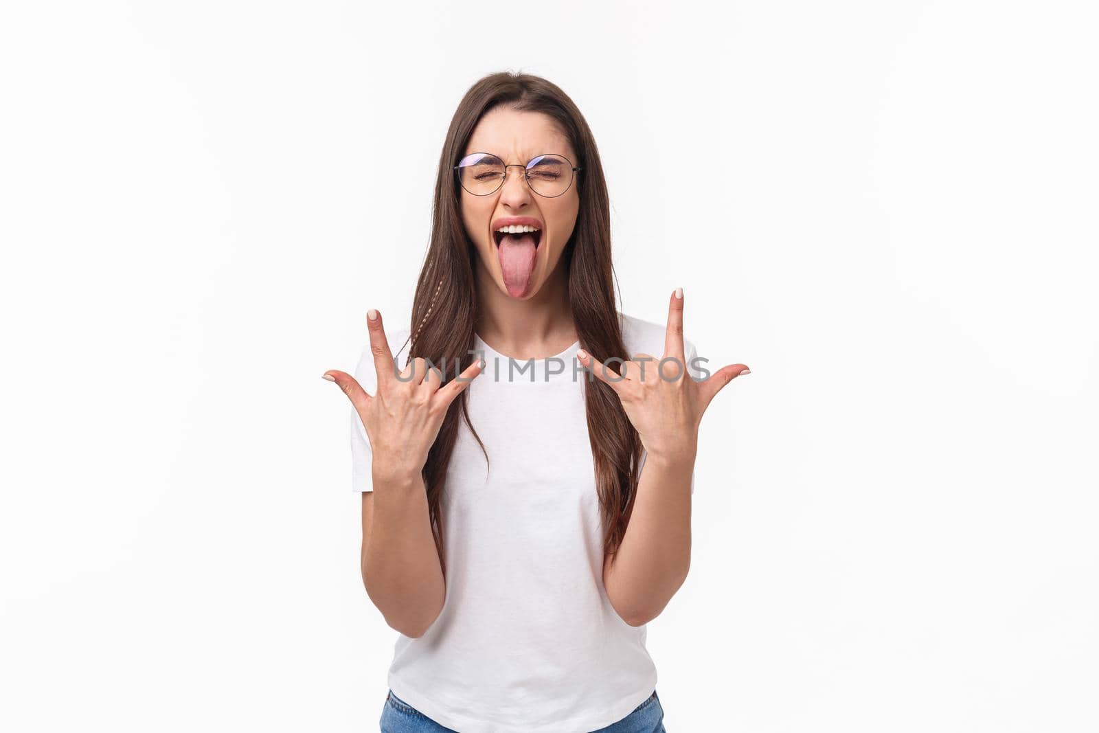 Rock-n-roll baby. Portrait of enthusiastic good-looking young girl having fun on awesome concert, show tongue close eyes and dancing with heavy metal sign, stand white background.