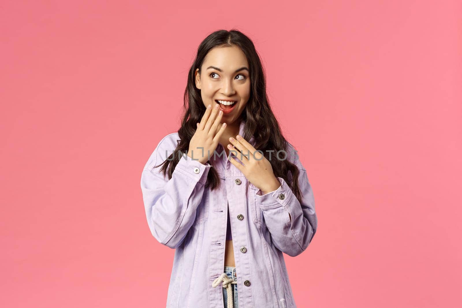 Lifestyle, spring and beauty concept. Portrait of stylish young pretty girl have an idea, giggle, smile and cover mouth, look upper left corner devious and thoughtful, have plan, pink background by Benzoix