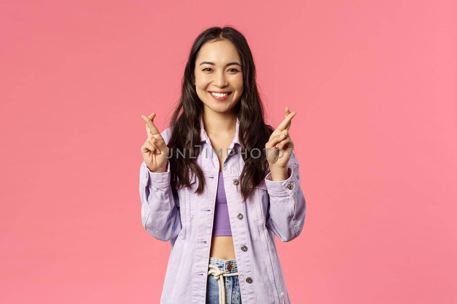 Portrait of excited attractive young korean girl having faith everything be good, keep fingers crossed while making wish, dreaming about desire come true, pink background by Benzoix