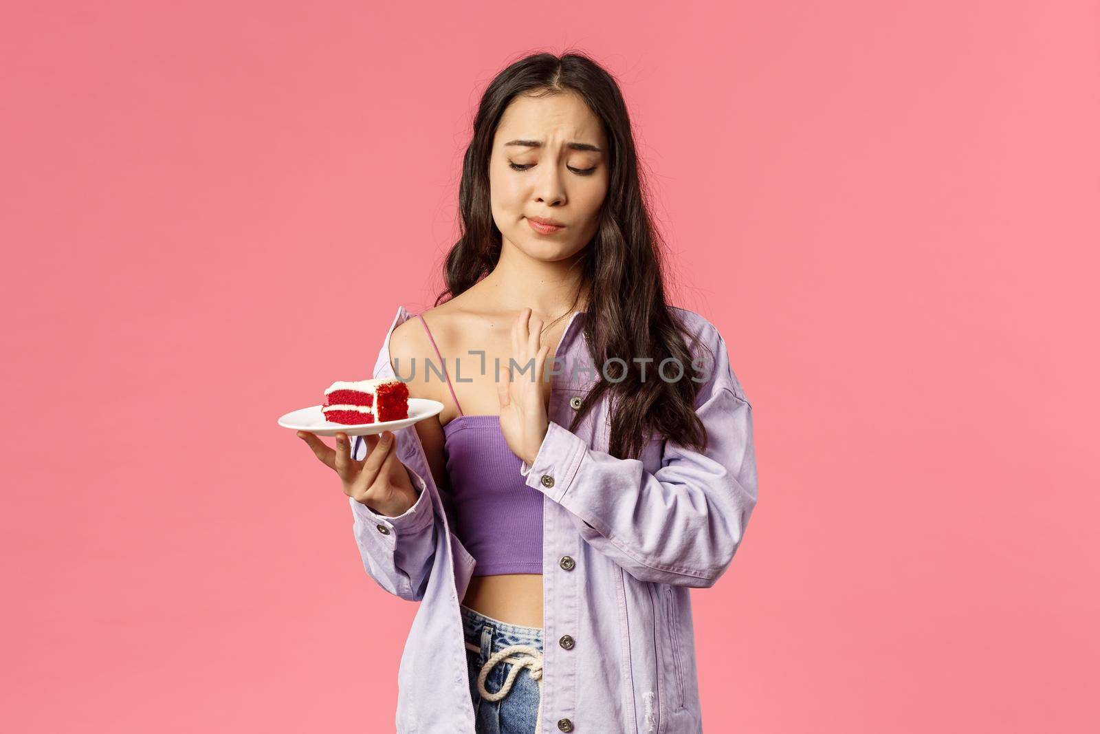 No thank you calories. Portrait of attractive asian girl taking care of her looks, saying no to delicious dessert, smirk show stop sign to cake, restrain herself eat after six, pink background by Benzoix